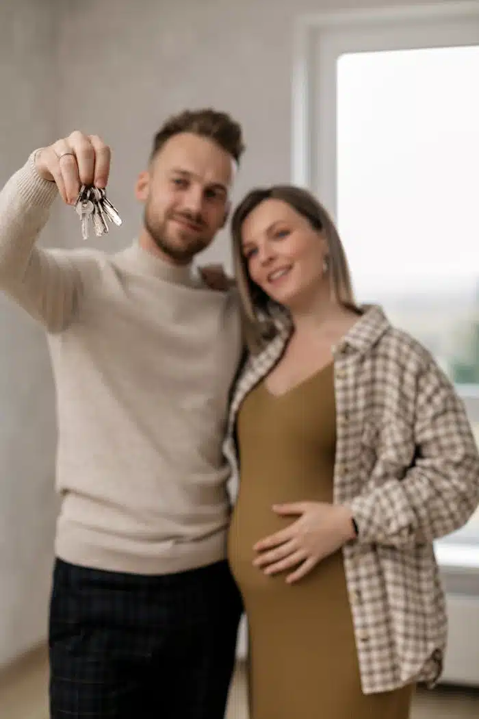 Man Holding Keys Beside a Pregnant Woman